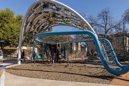 Modern playground with curved climbing structure at THE'68 Apartments, San Antonio, TX 78205