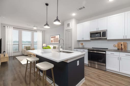 a kitchen with white cabinets and a large island with two stools at Birdie on Woodland Greens, Austin, 78726