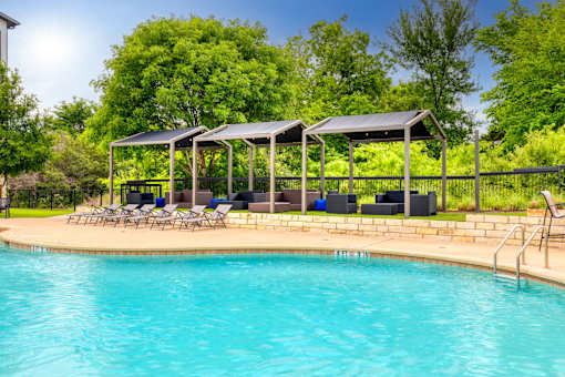 swimming pool with lounge chairs at the resort on a sunny day at Radius on Grove, Austin