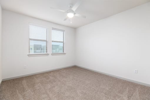 an empty room with two windows and a ceiling fan at Birdie on Woodland Greens, Austin, TX