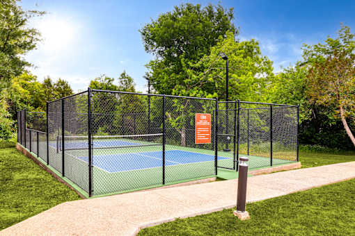 a tennis court with a fence around it on a sunny day at Radius on Grove, Texas, 78741