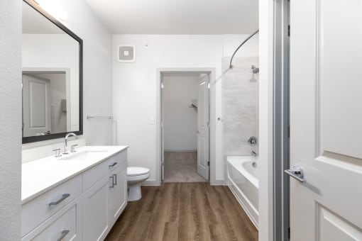 a bathroom with white cabinets and a shower and a sink and a toilet at Birdie on Woodland Greens, Austin, Texas