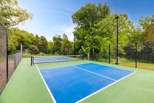 a tennis court with a fenced in area and a blue and green at Radius on Grove, Austin, TX, 78741