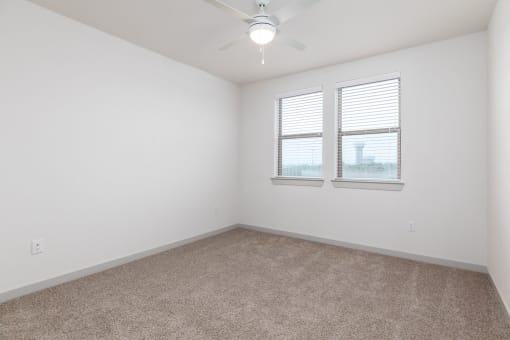 an empty room with two windows and a ceiling fan at Birdie on Woodland Greens, Austin, 78726