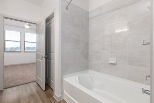 a bathroom with a tub and a shower and a door at Birdie on Woodland Greens, Austin, Texas