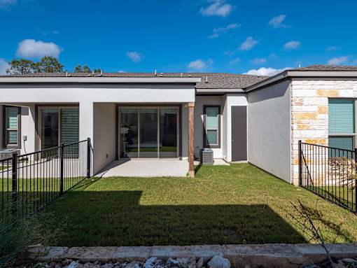 A modern house with a black fence and a green lawn.