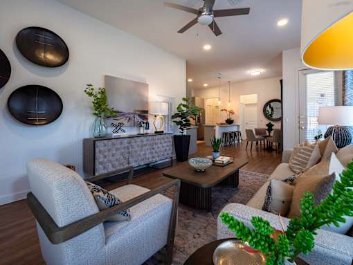A living room with a grey sofa, a wooden coffee table, and a ceiling fan.