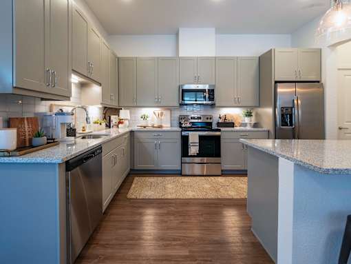 A modern kitchen with wooden floors and stainless steel appliances.