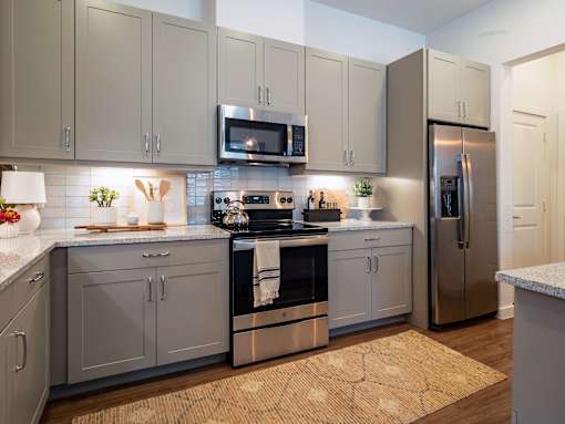 A kitchen with a refrigerator, microwave, and oven.