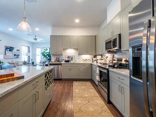 A modern kitchen with stainless steel appliances and wooden flooring.