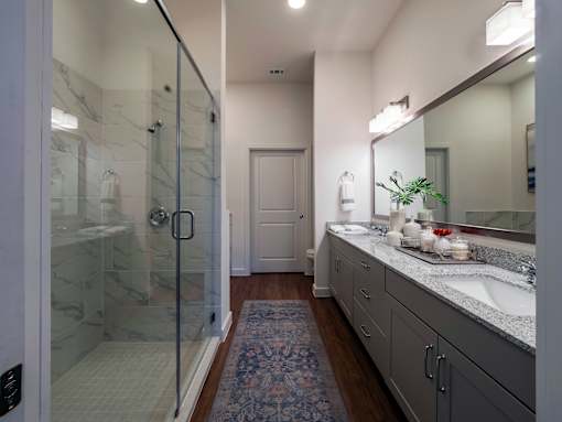 A bathroom with a glass shower door and a marble countertop.