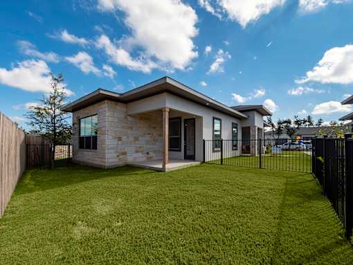 A modern house with a stone exterior and a black fence.