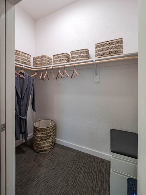 A laundry room with a washer and dryer, a basket, and clothes hanging up.