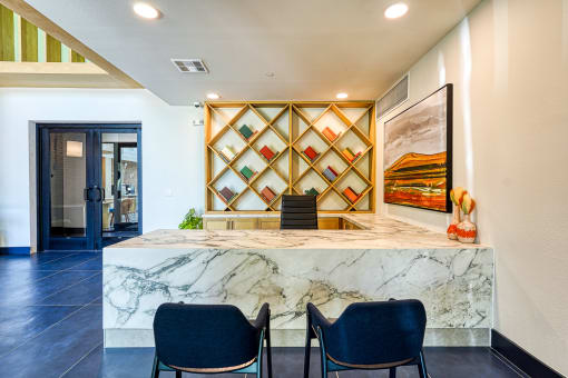 a lobby with a marble counter and blue chairs at Birdie on Woodland Greens, Texas