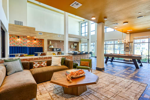 a clubhouse with couches and a table with a poolat Birdie on Woodland Greens, Austin, Texas
