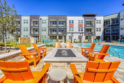 A pool area with orange chairs and a fountain in the middle.