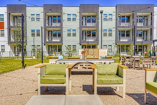 A patio with a table and chairs in front of apartment buildings.