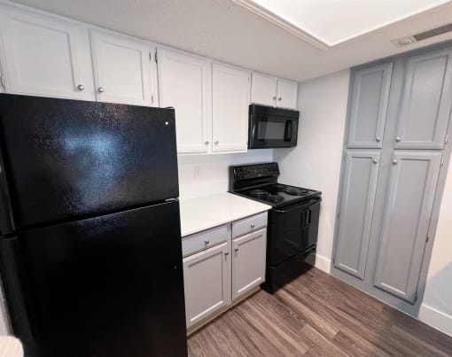 a kitchen with black appliances and white cabinets at Northchase, Austin, TX