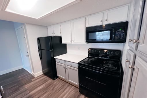 a kitchen with black appliances and white cabinets at Northchase, Austin, TX, 78753