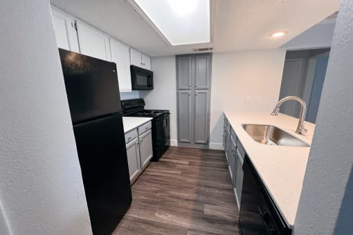 a kitchen with white cabinets and black appliances at Northchase, Austin, TX