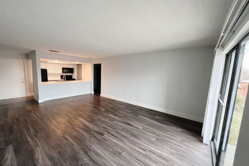 an empty living room with wood flooring and a kitchen at Northchase, Texas, 78753