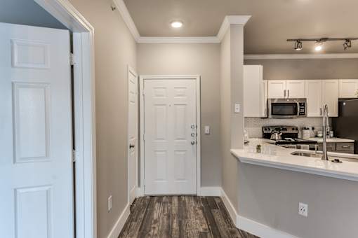 A kitchen with white cabinets and a white door at Rosemary Apartments, Texas, 77384