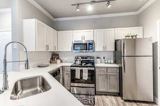 A modern kitchen with a stainless steel refrigerator, microwave, and oven at Rosemary Apartments, Conroe, TX