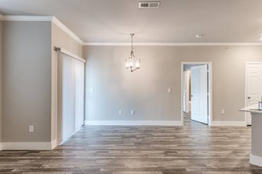 A room with a wooden floor and a chandelier hanging from the ceiling at Rosemary Apartments, Conroe