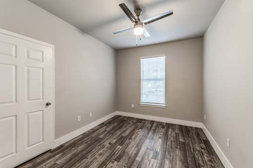 A room with a ceiling fan and wooden flooring at Rosemary Apartments, Texas