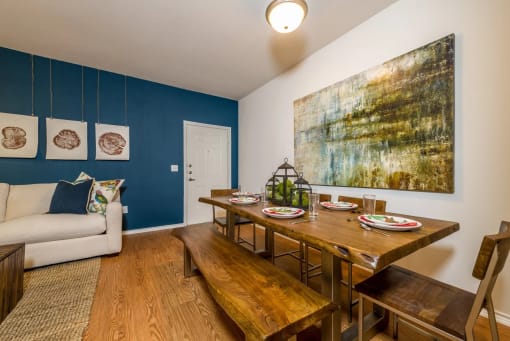 a dining room with a wooden table and bench and a couch in the background at Villa Espada Apartments, San Antonio, 78221