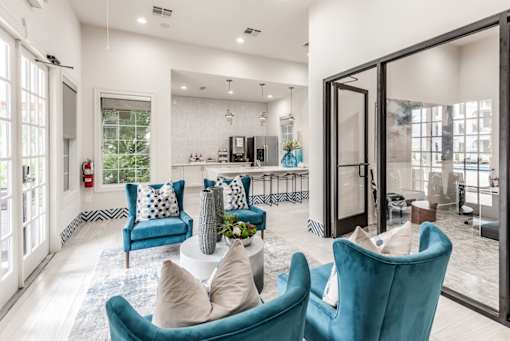A living room with blue chairs and a white couch at Rosemary Apartments, Conroe, TX