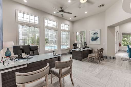 A well-lit office with a desk, chairs, and a ceiling fan at Rosemary Apartments, Conroe