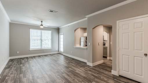 A spacious room with wooden flooring and a white door at Rosemary Apartments, Conroe, TX, 77384