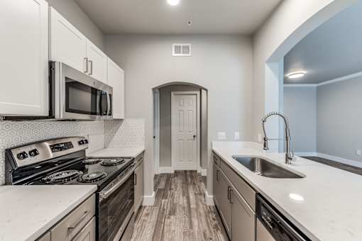 A kitchen with a stove, microwave, and sink at Rosemary Apartments, Conroe, Texas