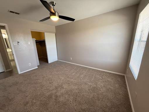 A room with a ceiling fan and carpeted floor.