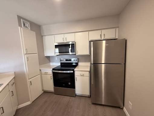 A kitchen with a stainless steel refrigerator, oven, and microwave.