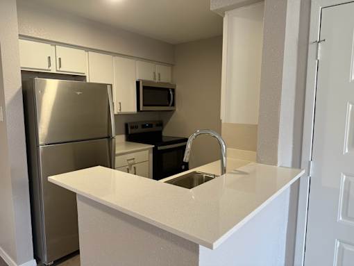 A kitchen with a stainless steel refrigerator and a white countertop.