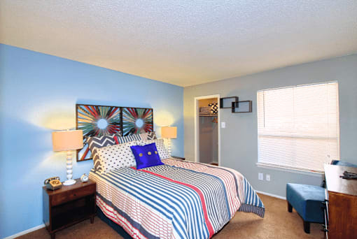 A bedroom with a bed, nightstand, and window.