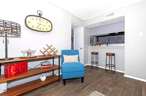 A blue chair sits in a room with a clock on the wall.