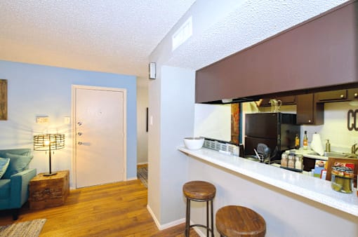 A kitchen area with a bar stool and a counter with a coffee maker.