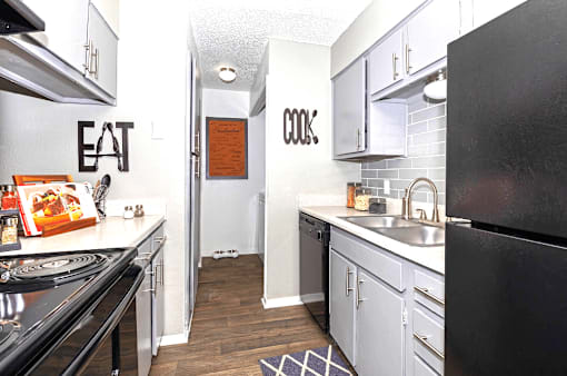 A kitchen with a black refrigerator and a white counter top.