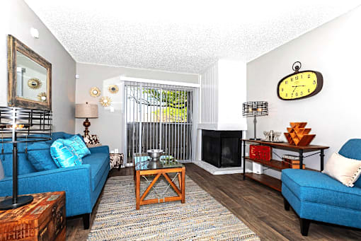 A living room with a blue couch, a wooden coffee table, and a large clock on the wall.