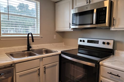 a kitchen with a sink and a stove and a microwave at Ivy Plains at Brooks Apartments, San Antonio , TX, 78223