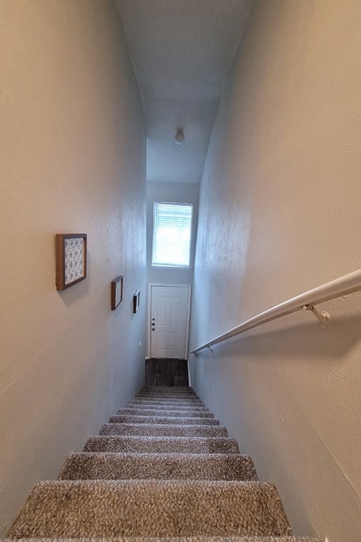 a stairway with a carpeted landing and a window on the top of it at Ivy Plains at Brooks Apartments, San Antonio , 78223