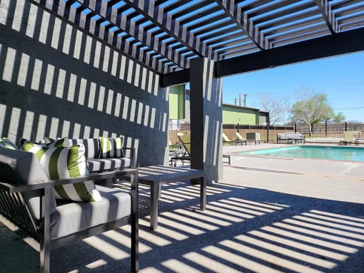 a patio with chairs and a table next to a pool at Ivy Plains at Brooks Apartments, San Antonio