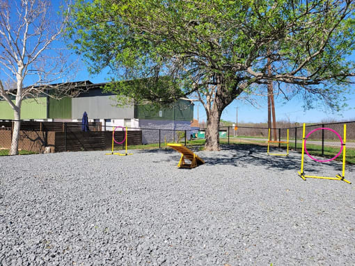 a playground with swings and a tree in front of a building at Ivy Plains at Brooks Apartments, San Antonio , TX, 78223