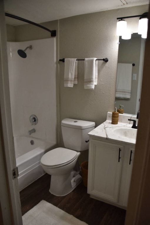 a bathroom with a toilet and a tub and a sink at Ivy Plains at Brooks Apartments, Texas, 78223