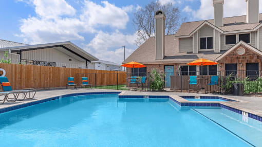 our apartments have a swimming pool with chairs and umbrellas at Tranquility Grove, Houston, 77090