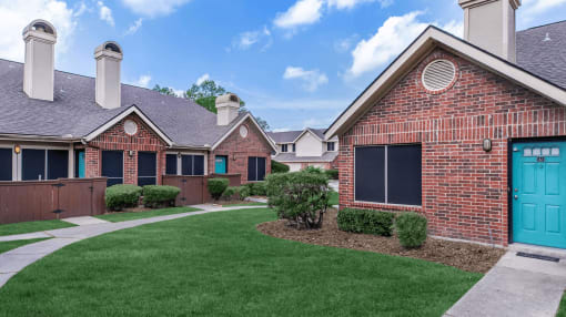 a yard in front of a brick house with a blue door at Tranquility Grove, Houston, TX 77090