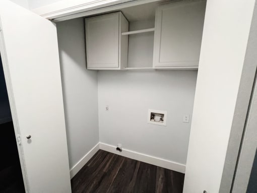 a room with white cabinets and a white wall and wooden floors at Northchase, Austin, TX